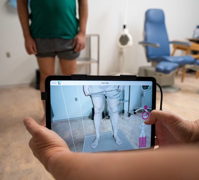 Billede af en iPad-lignende scanner, der tager billede af et par bare ben